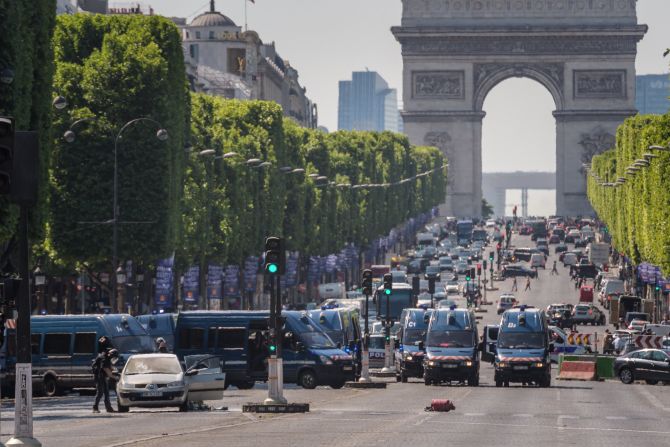 Police in Paris gather on the Champs-Elysees boulevard after an armed man intentionally rammed a car into a police van, authorities said on Monday, June 19. France's interior minister told reporters that the car contained weapons and explosives. The suspect later died.