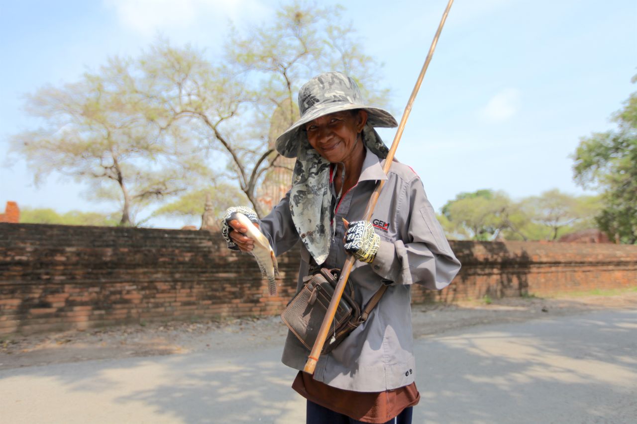 A woman shows off a fish caught in a lake outside Wat Phra Ram.