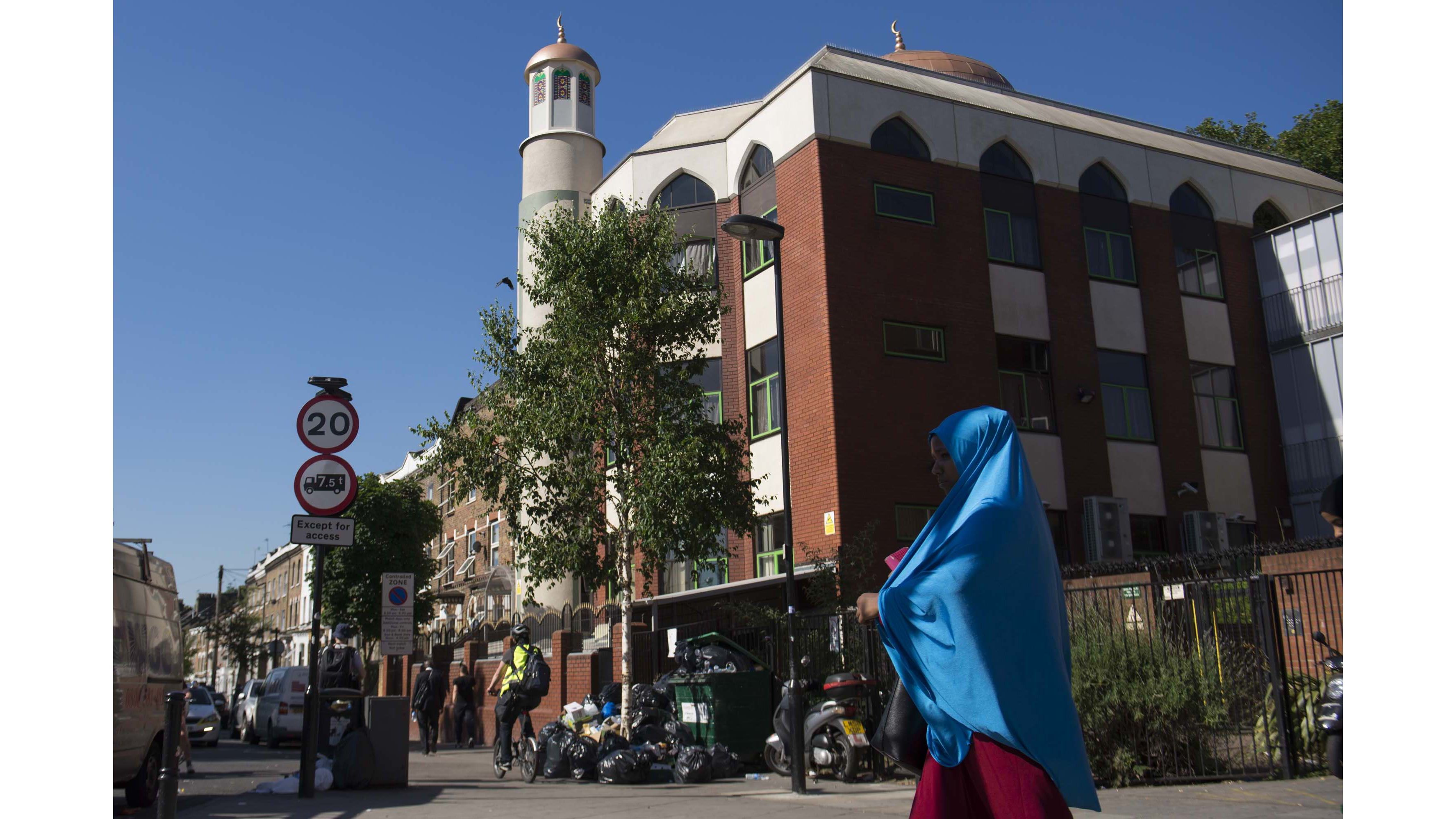 A woman in a blue hijab walks past the five-story red brick Finsbury Park Mosque -- the scene of Monday's attack.