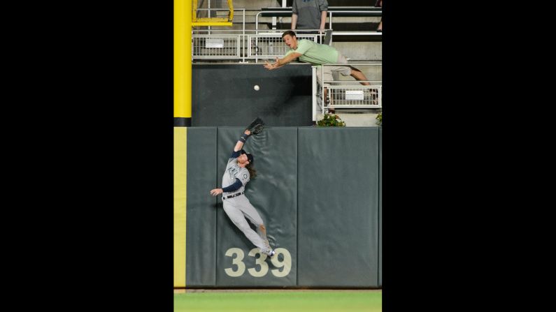 Seattle outfielder Ben Gamel tries to catch a fly ball in Minneapolis on Tuesday, June 13. (As does a fan.)