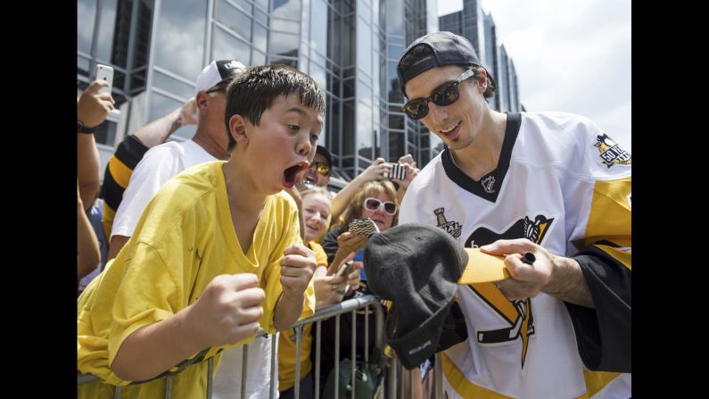 A young fan is excited as Pittsburgh goalie Marc-Andre Fleury signs a hat for him during the hockey team's Stanley Cup parade on Wednesday, June 14.