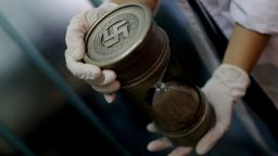 A member of the federal police holds an hourglass with Nazi markings at the Interpol headquarters in Buenos Aires, Argentina, Friday, June 16, 2017. In a hidden room in a house near Argentina's capital, police discovered on June 8th the biggest collection of Nazi artifacts in the country's history. Authorities say they suspect they are originals that belonged to high-ranking Nazis in Germany during World War II. (AP Photo/Natacha Pisarenko)