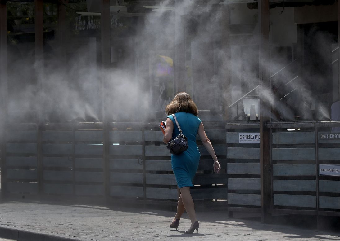 A woman walks through cooling mist in Tempe on June 19.