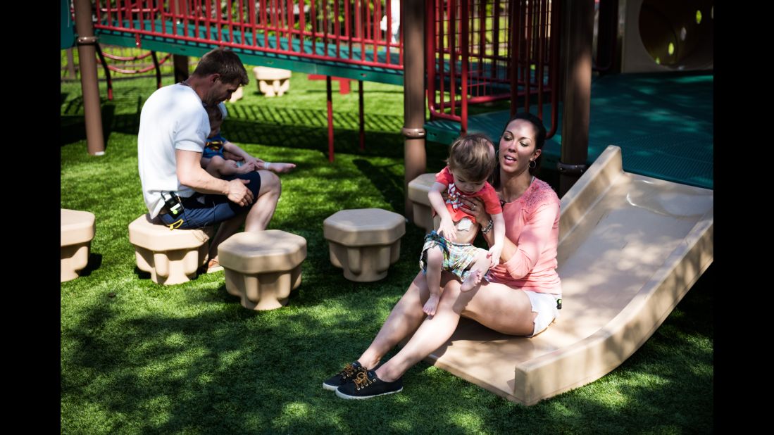 Nicole McDonald plays with her son Anias as Christian McDonald holds Jadon on a playground outside Blythedale Children's Hospital. 