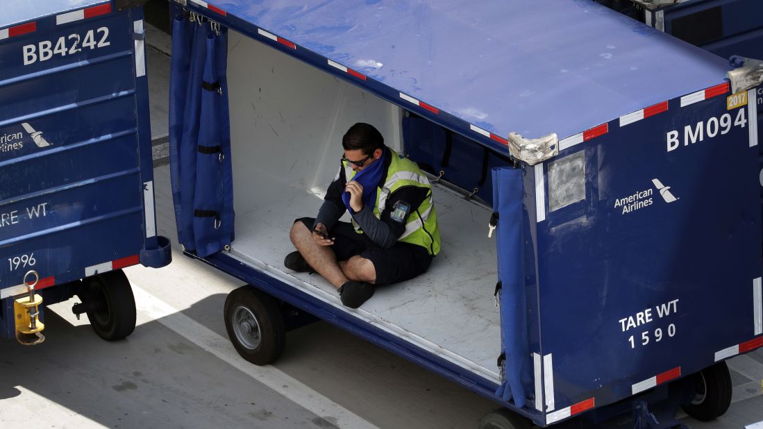 An American Airlines grounds crew member sits in a luggage cart to avoid the heat in Phoenix on June 20.
