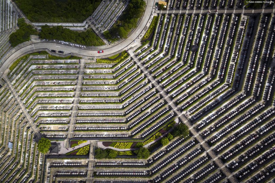 A red car snakes by a Hong Kong cemetery, adding a playful sense of scale to this aerial shot. 