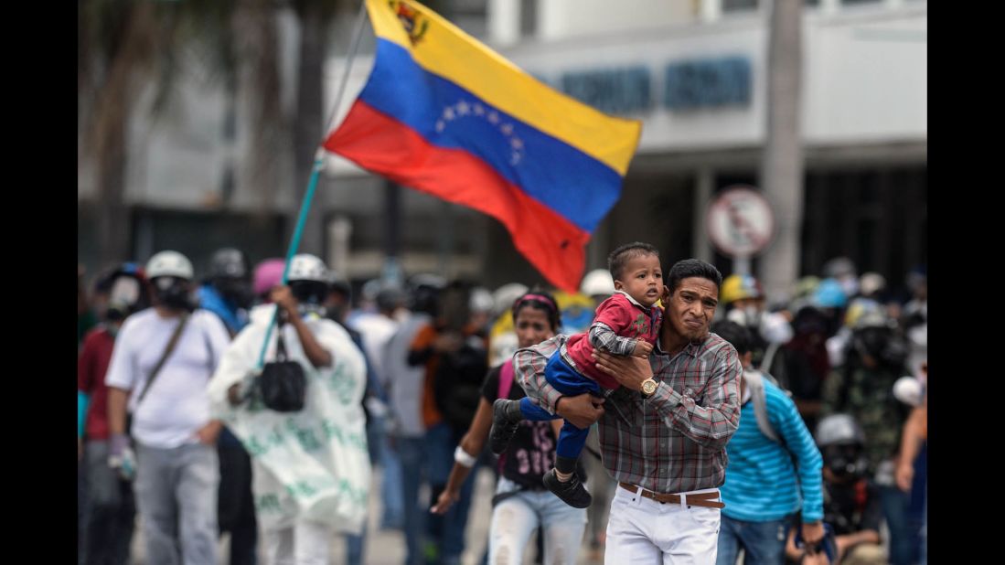 People flee during a clash between opposition demonstrators and riot police in Caracas on June 19.