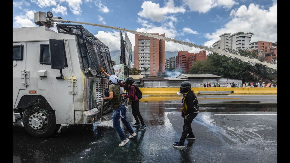 Opposition activists stand in front of a riot police vehicle during a demonstration against the government of President Nicolas Maduro on June 19.