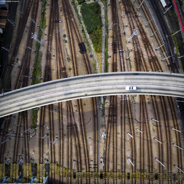 Capturing a flyover intersecting railway tracks, the image reveals the multi-layered transportation networks and sophisticated infrastructural development in Hong Kong which have contributed to city's rapid development.