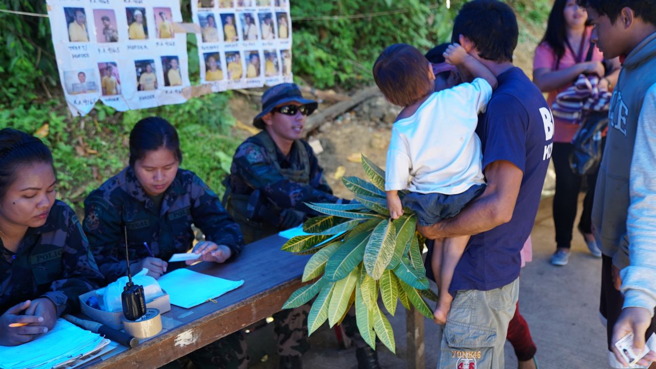 Passengers at a checkpoint into Iligan City. Jeepney riders are required disembark from their public transport and show ID before reboarding on the other side. 