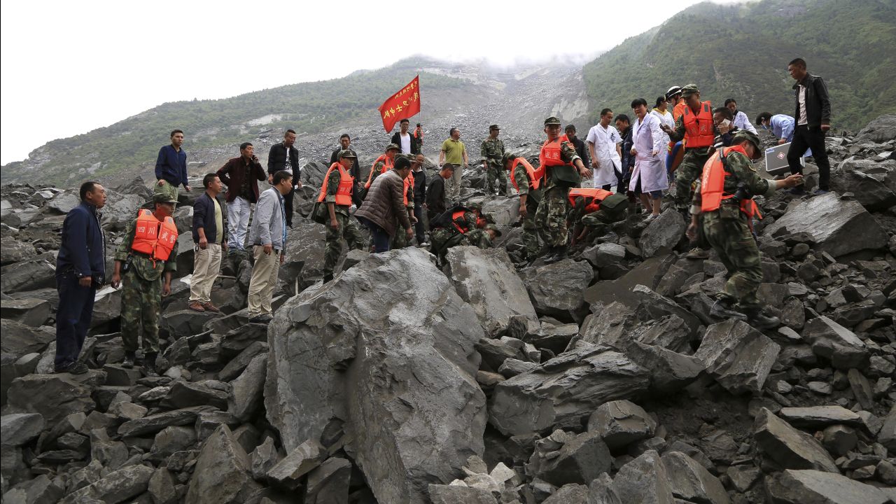 Emergency personnel swarm the area of landslide looking for survivors on June 24.