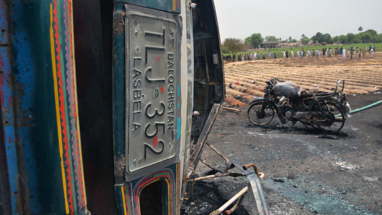 A burned motorcycle stands next to the wreckage of the tanker truck.
