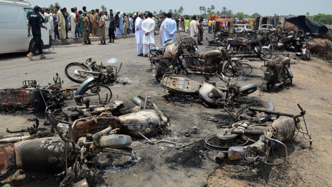 People gather behind burned motorcycles and vehicles at the scene of the explosion. 