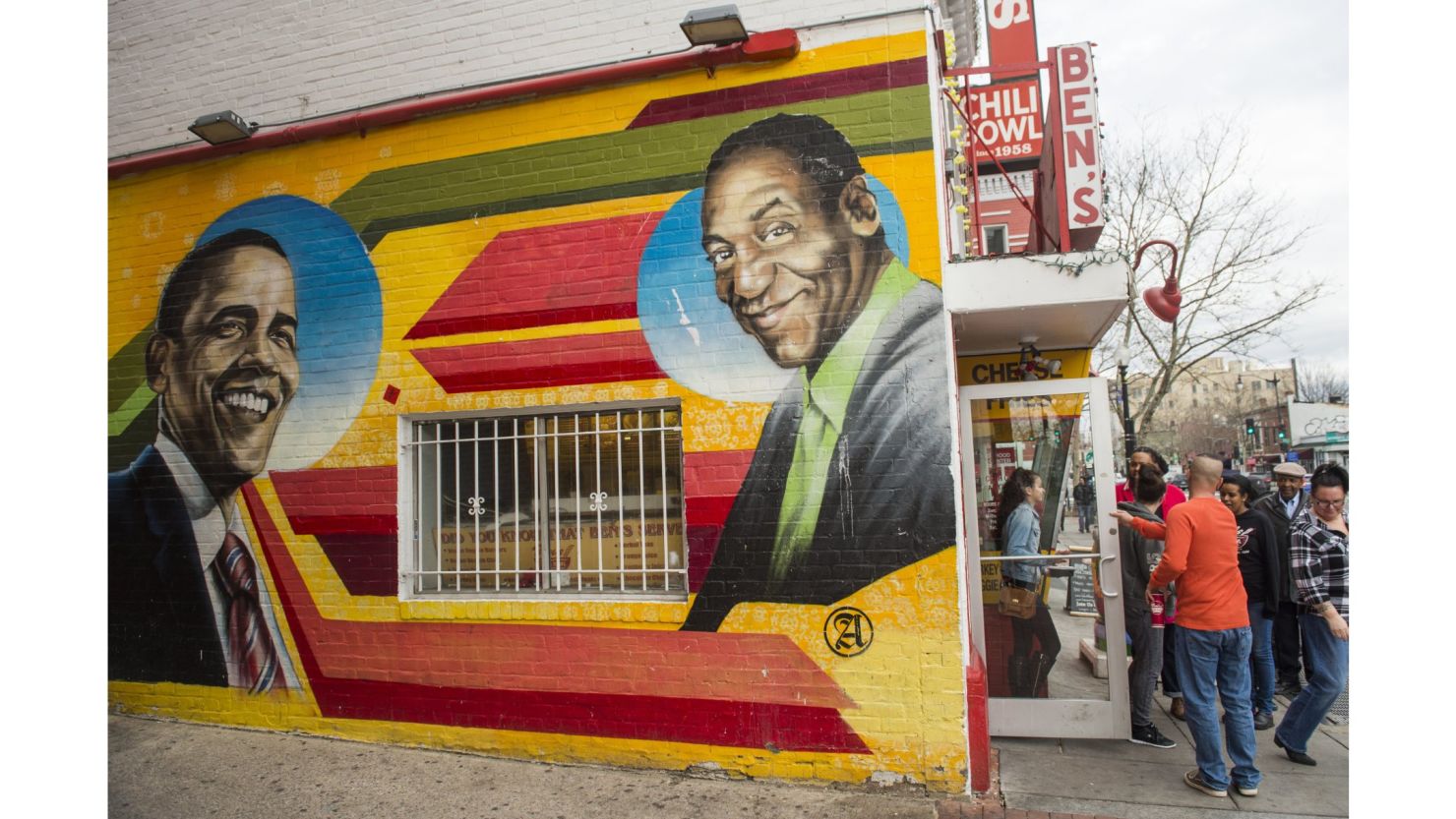 People walk past a mural of comedian Bill Cosby on the side of Ben's Chili Bowl in Washington, D.C. The mural has since been repainted.