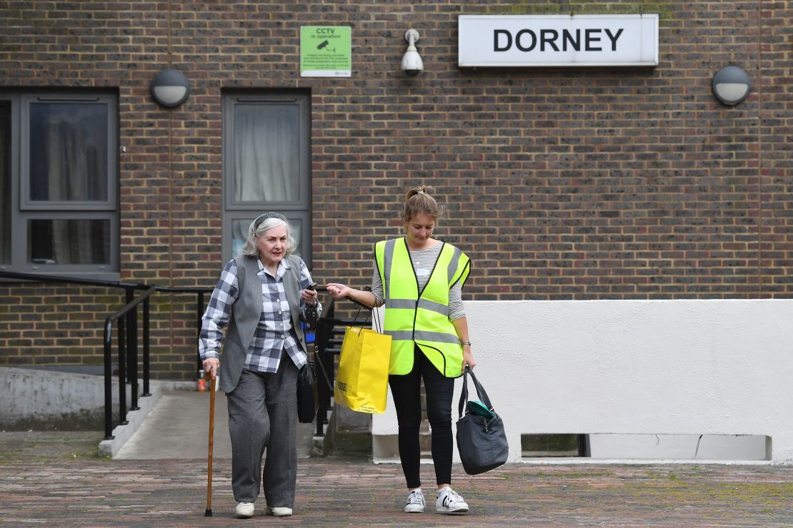 A council worker helps a resident leave Dorney Tower residential block on the Chalcots Estate in north London on June 25, 2017.
