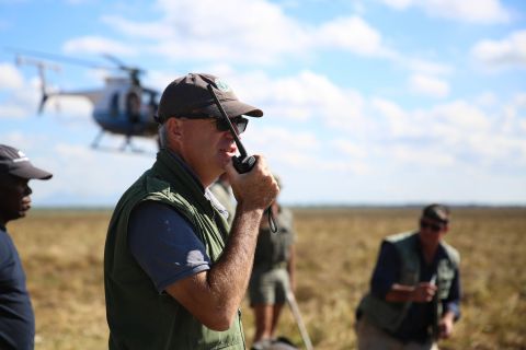 Wildlife vet Kester Vickery radios the helicopter team circling above. The air and ground teams work together to corral, dart and capture entire herds safely. 