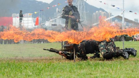 PLA soldiers crawl under a burning frame during a demonstration at the open day of the Chinese People's Liberation Army (PLA) Navy Base at Stonecutter Island in Hong Kong on July 1, 2016.