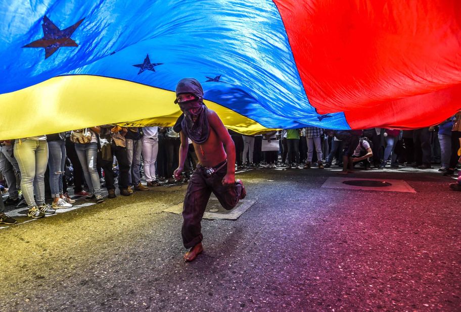 A boy runs under a national flag during a June 27 protest in Caracas.