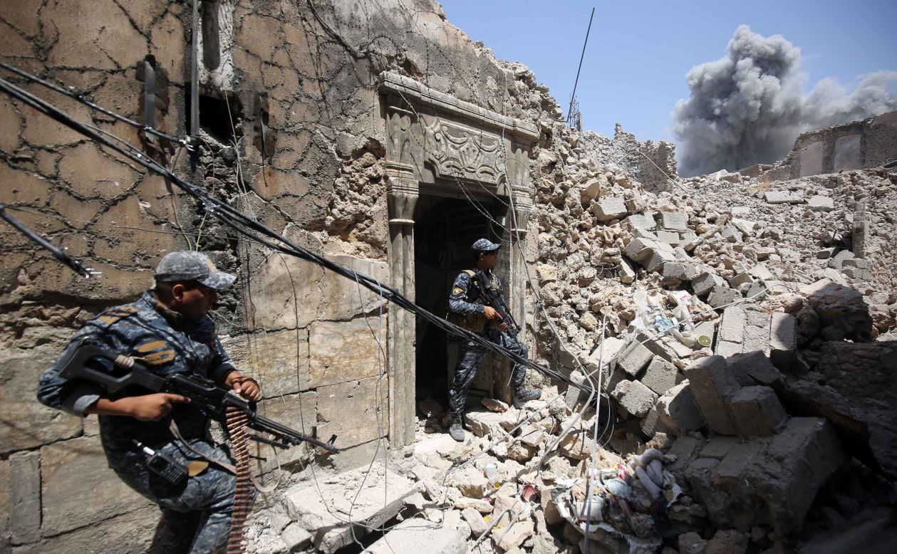 Members of the Iraqi Federal Police hold a position as US-led coalition forces advance through the Old City on Wednesday, June 28.