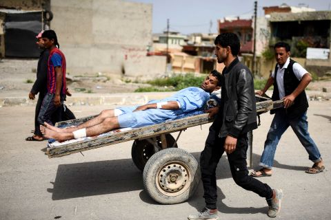 A wounded man is transported in western Mosul on Friday, April 21.