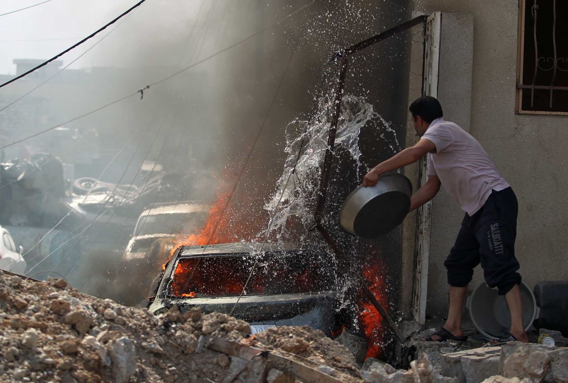 An Iraqi man tries to extinguish a burning car during fighting in Mosul's western Rifai neighborhood on Tuesday, May 16.