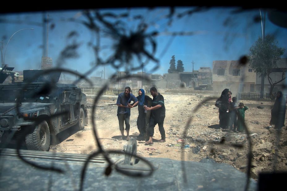 Displaced Iraqis make their way through rubble after evacuating their homes in a neighborhood of west Mosul on Wednesday, May 17.