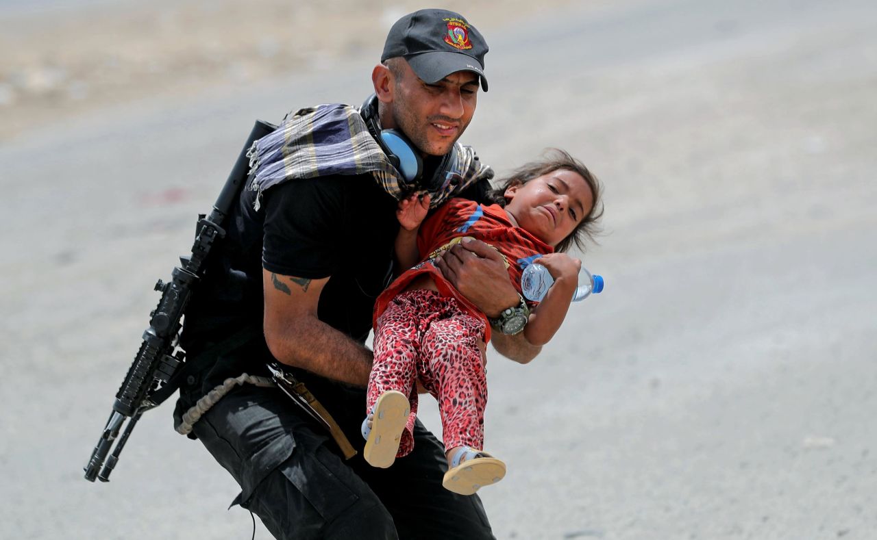 An Iraqi soldier helps transport a girl as residents flee their homes west of Mosul on Friday, May 26.