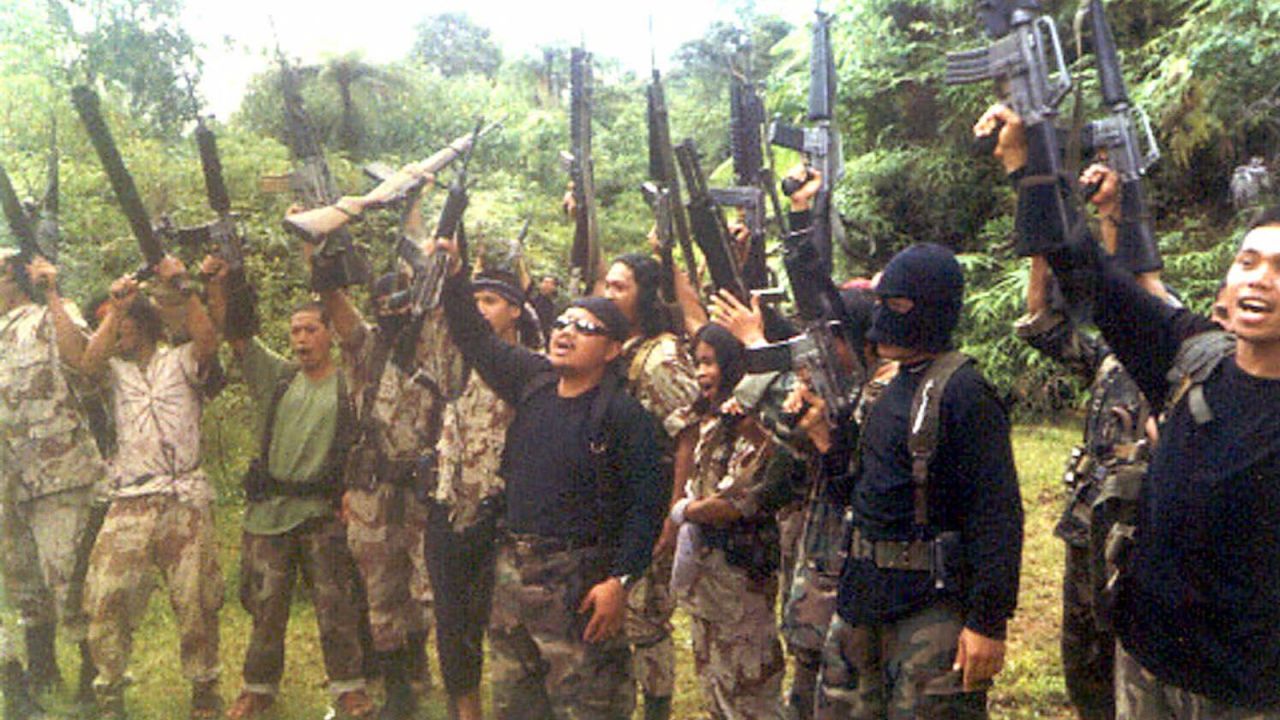Members of the extremist group, Abu Sayyaf Group (ASG) raise their firearms as they shout slogans in March, 2000 at their hideout in Basilan, 890 kilometers (560 miles) southeast of Manila. Abu Jihad is the masked militant in the foreground of the shot.