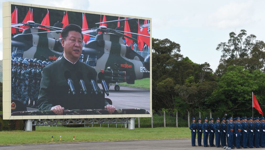 Chinese President Xi Jinping (on screen) reviews troops from a car during a military parade in Hong Kong on June 30, 2017.
