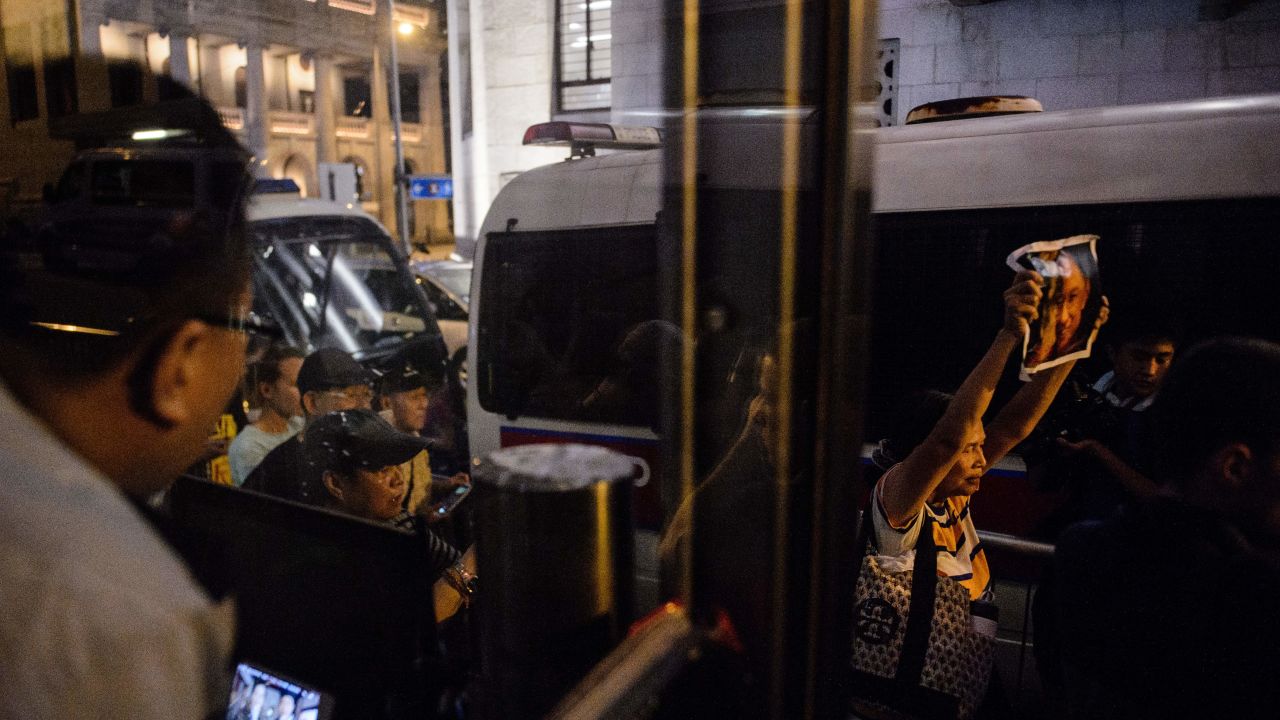 A member of security, left, looks on as an activist, right holds a poster of terminally-ill Nobel laureate Liu Xiaobo on the sidelines of a vigil for him in Hong Kong on June 29, 2017.
