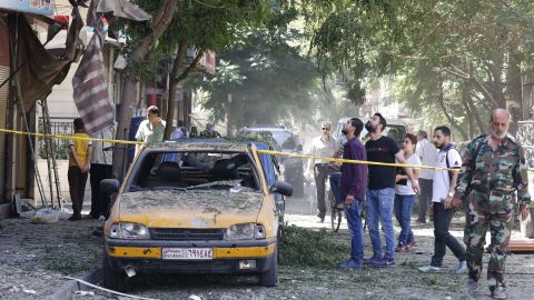 Syrian men look at a cordoned off area at the site of a suicide bomb attack in the capital Damascus' eastern Tahrir Square district.
