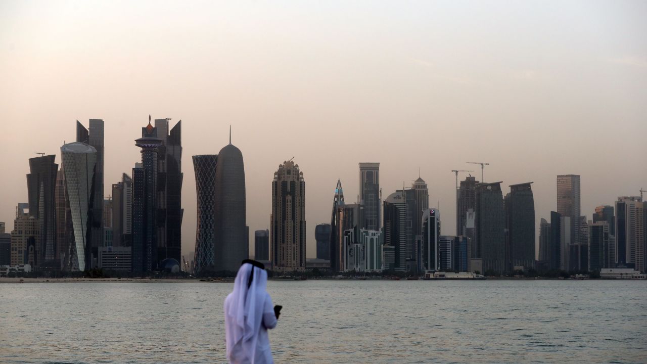 A man looks at his phone on the corniche in the Qatari capital Doha on July 2, 2017. / AFP PHOTO / STR        (Photo credit should read STR/AFP/Getty Images)