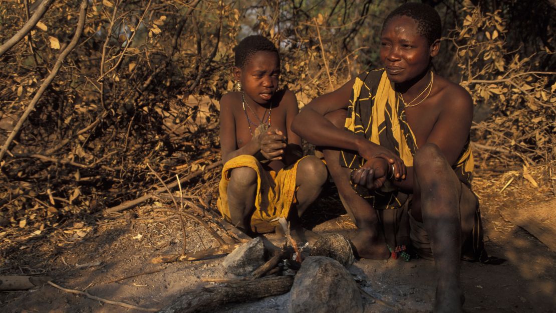 Hadza woman and child sitting at a fire, Lake Eyasi, Tanzania.