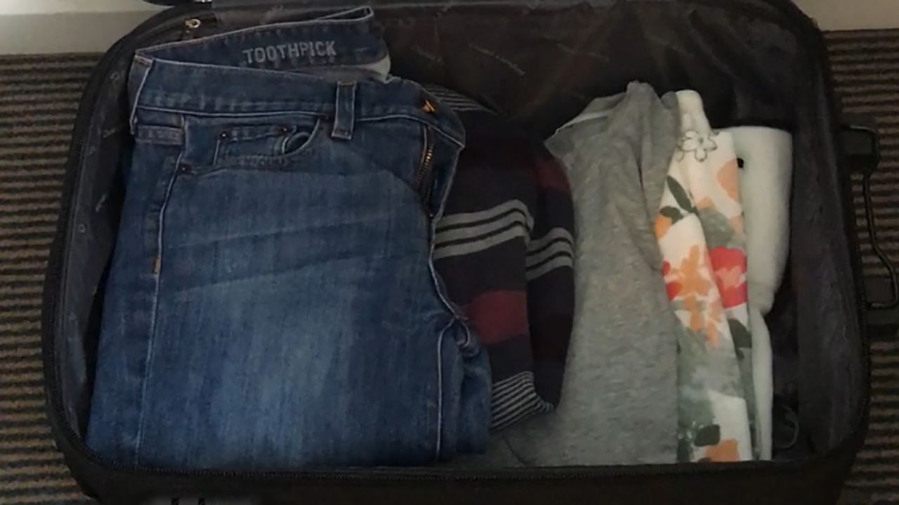 A single suitcase accompanies a few clothes in the wardrobe of the Alveses' hotel room. 