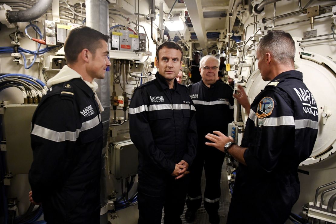 Macron (center) stands with Capt. Jerome Halle, the commanding officer.