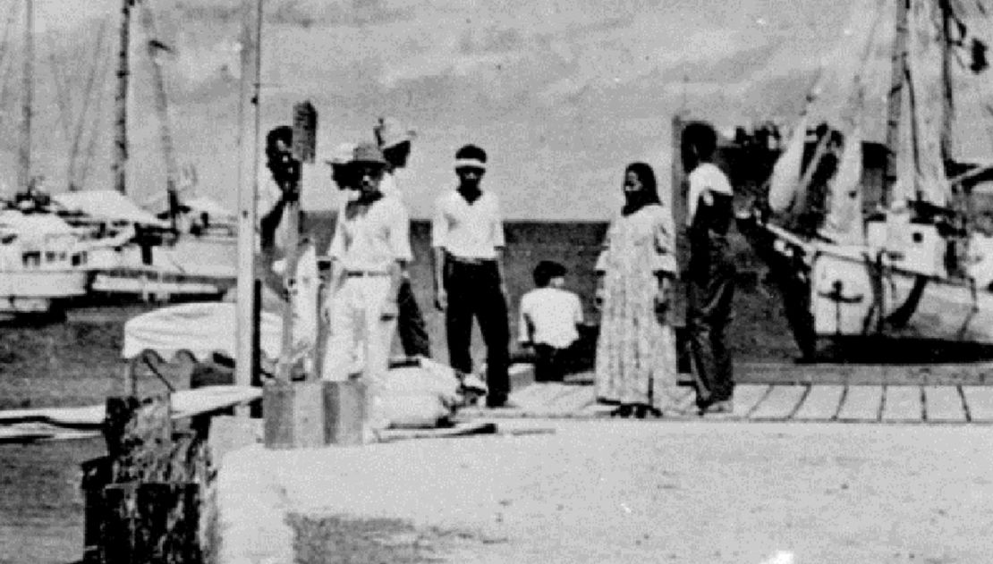 Some experts believe the figure on the far left is Fred Noonan and the person sitting, facing away from the camera, is Amelia Earhart.