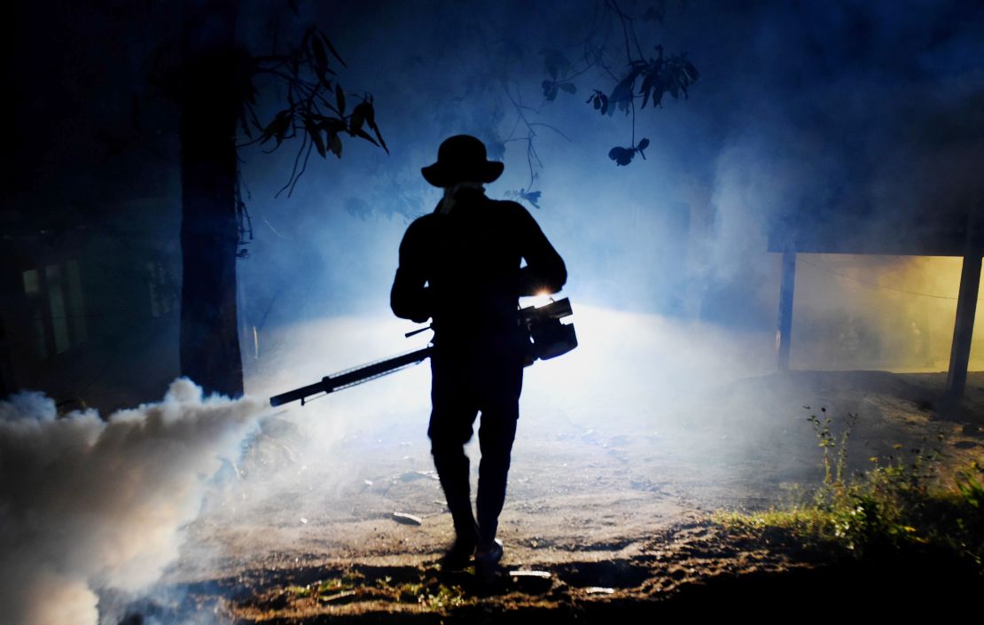 A Sri Lankan health worker sprays a neighborhood with a fog used to ward off mosquitos in January.