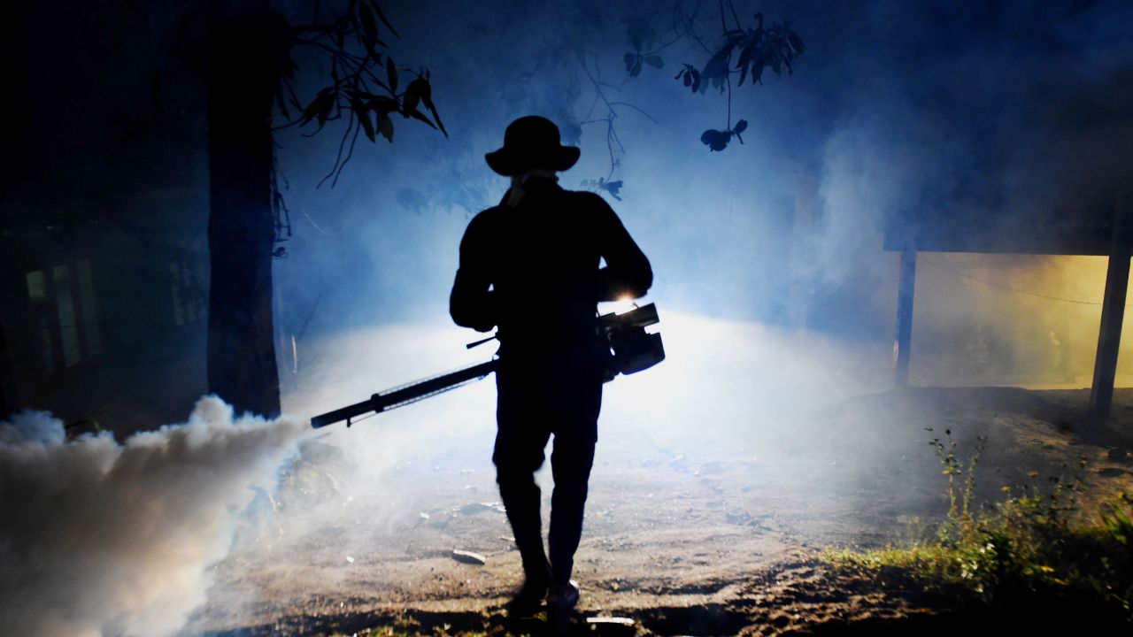 A Sri Lankan health worker sprays a neighborhood with a fog used to ward off mosquitos in January.