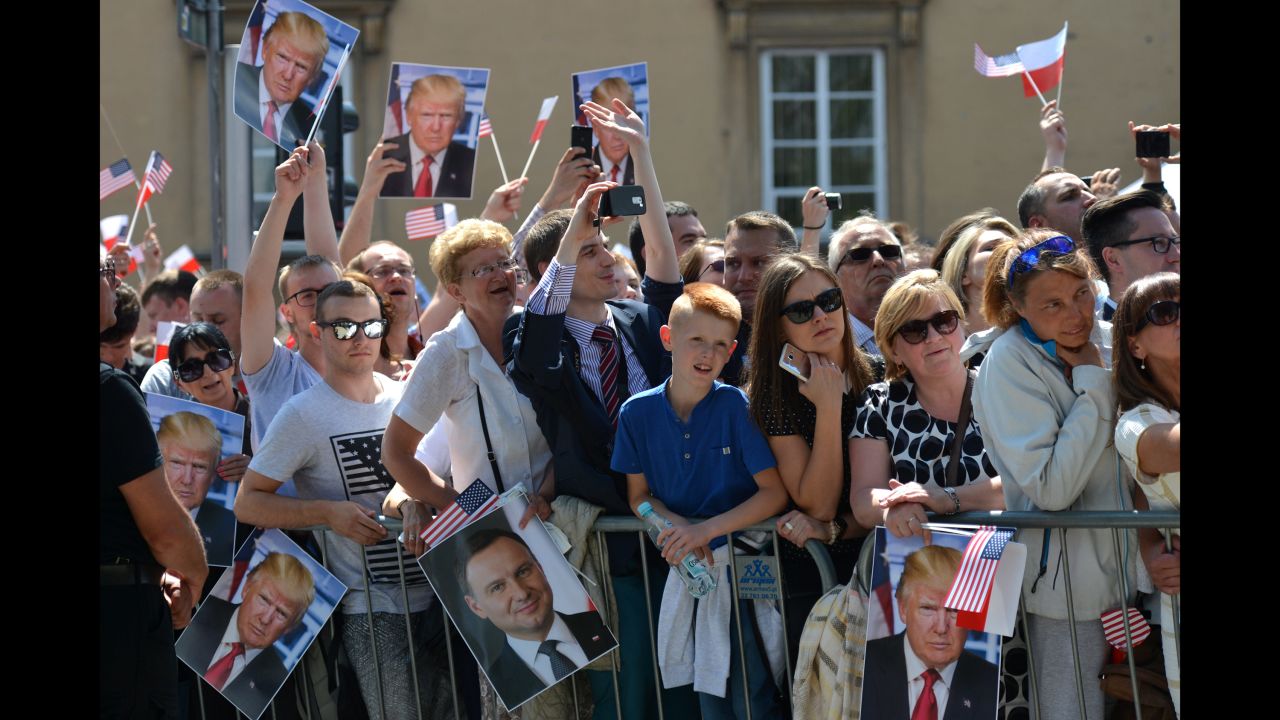 People hold up pictures of Trump during his speech in Warsaw. 