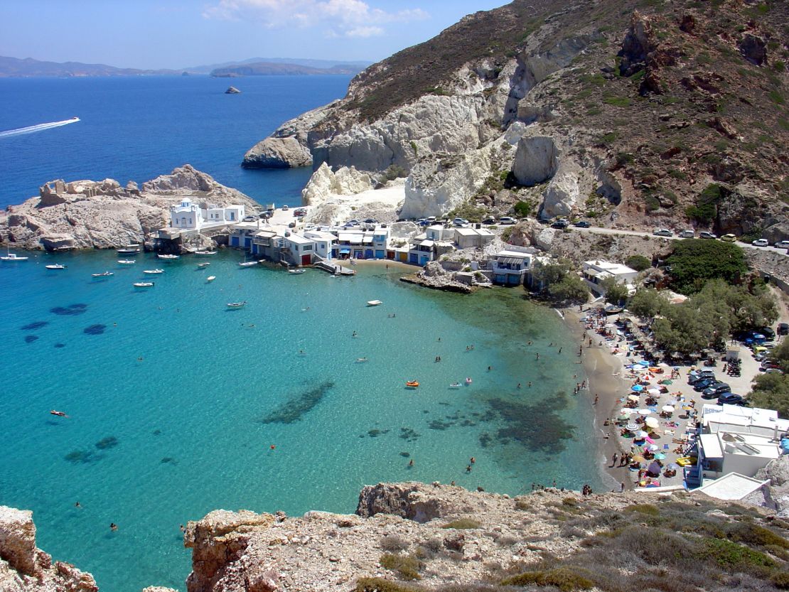 White-washed cube houses and colored boatsheds frame a sandy beach at Firopotamos.