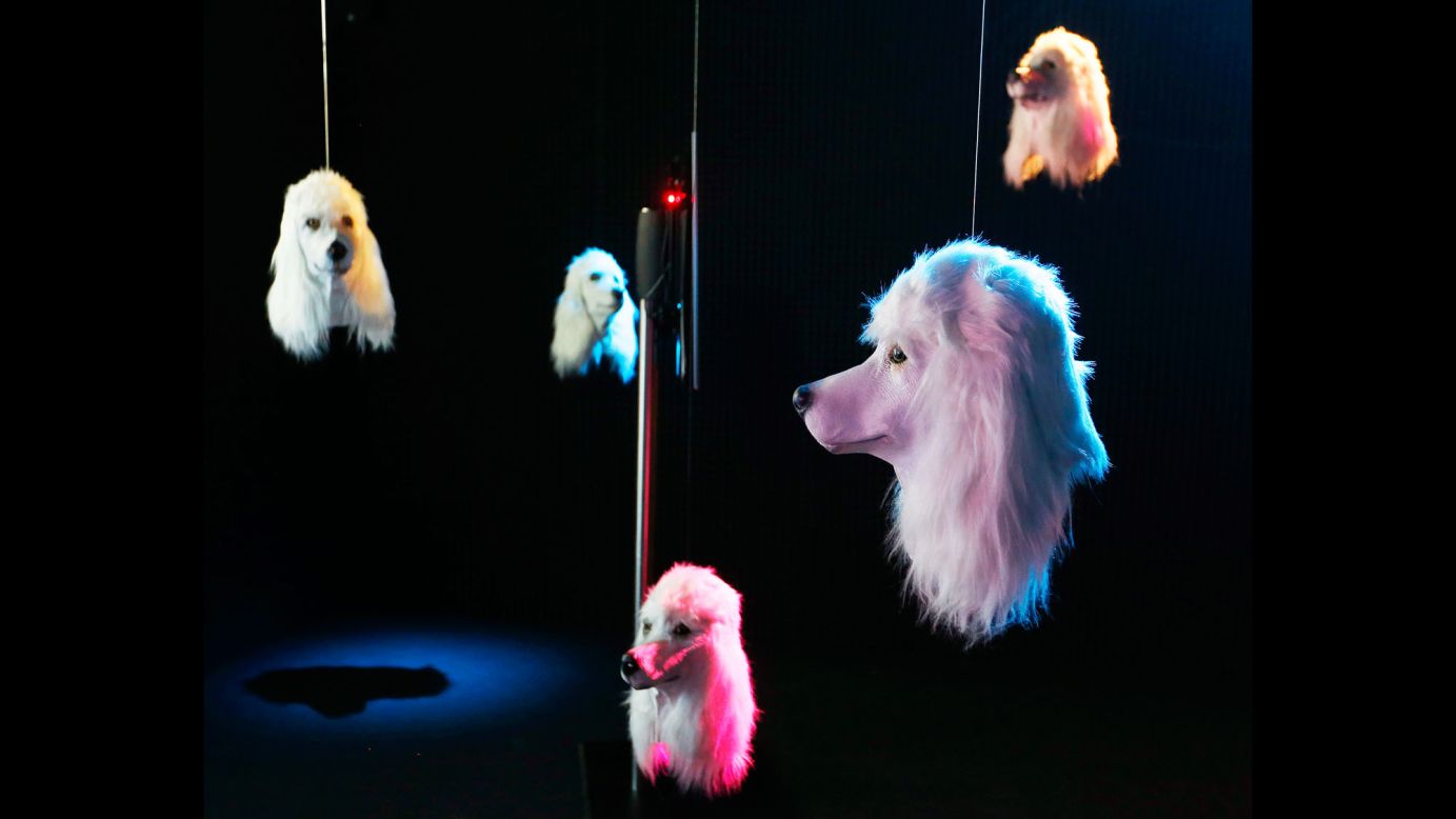 Artificial dog heads, part of Heather Phillipson's art installation "100% Other Fibres," sway in a dark room of the Schirn museum in Frankfurt, Germany, on Monday, July 3.