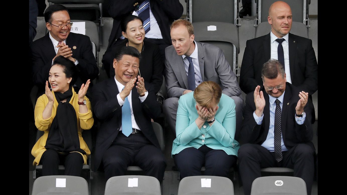 German Chancellor Angela Merkel puts her head in her hands as she watches a youth soccer game in Berlin with Chinese President Xi Jinping and his wife, Peng Liyuan, on Wednesday, July 5. The game was played between the under-12 teams of Germany and China.