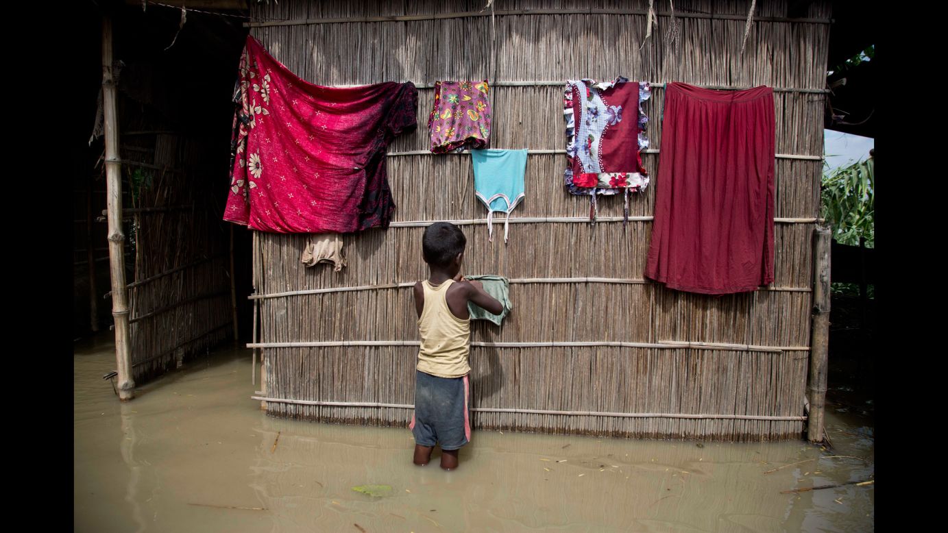 A boy dries clothes outside his house, which was partially submerged in floodwaters in Burgaon, India, on Wednesday, July 5. Heavy rains have triggered floods and landslides in parts of the country's remote northeast.