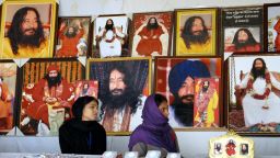 Indian followers of deceased guru Ashutosh Maharaj Divya Jyoti Jagriti Sansthaan sit in front of posters bearing his image.