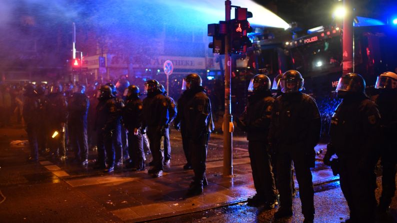 Police stand guard in the street while protesters erect barricades July 7 in Hamburg.