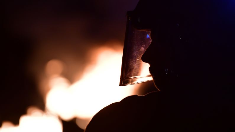 An officer looks on as barricades burn in front of the Rote Flora center.