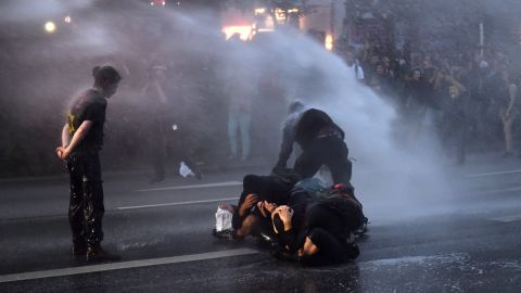Riot police use a water cannon on demonstrators.