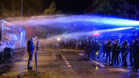 A demonstrator is sprayed by water canons.