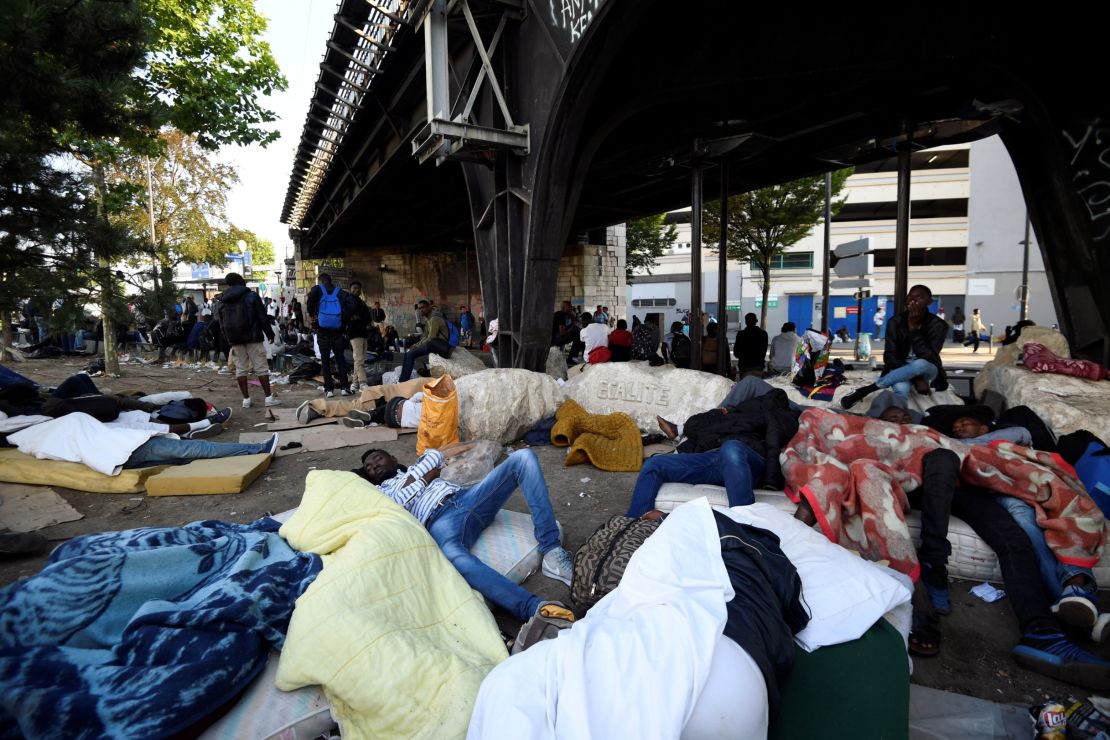 Migrants and refugees rest by a railway bridge during the evacuation.