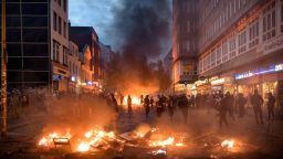 HAMBURG, GERMANY - JULY 07:  Demonstrators react next to a burning crush barrier during a demonstration against the G20 Summit on July 7, 2017 in Hamburg, Germany. Leaders of the G20 group of nations are arriving in Hamburg today for the July 7-8 economic summit and authorities are bracing for large-scale and disruptive protest efforts. (Photo by Thomas Lohnes/Getty Images)